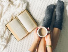 Reading and holding coffee with blanket
