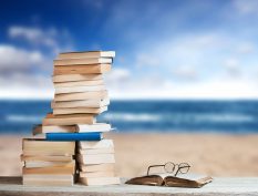 Books stacked beside a beach