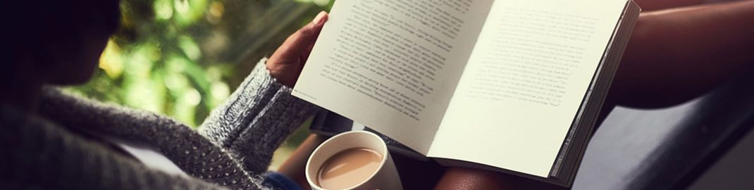 Reading by a window with a cup of coffee
